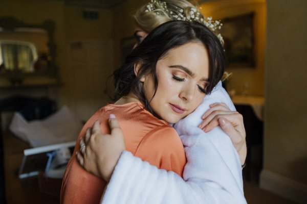 Bride hugs bridesmaid wearing orange loungewear