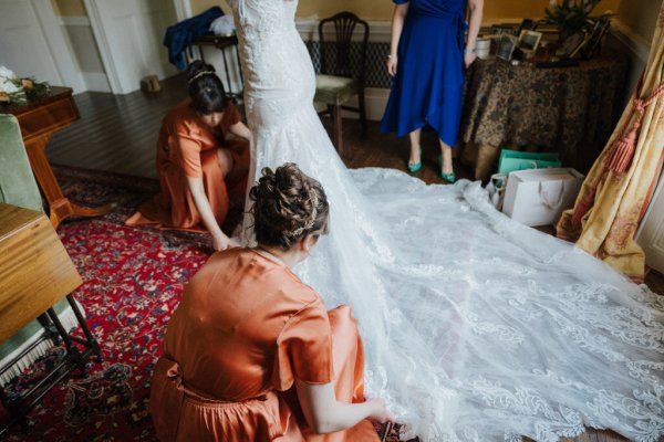 Bridesmaids help bride get ready long wedding dress train bridal gown