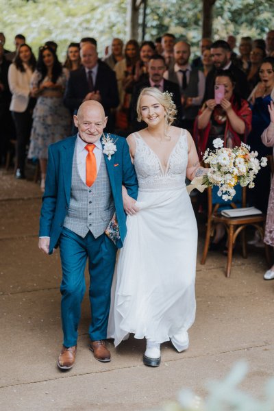 Father of the bride walks up aisle flowers