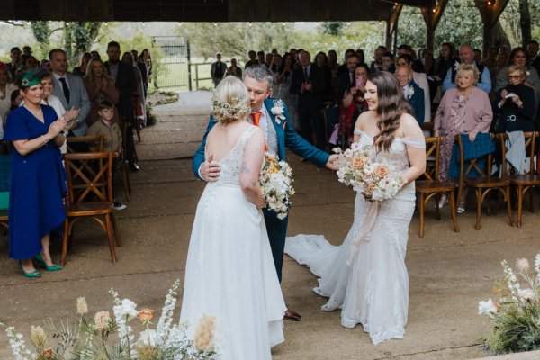 Brides holding flowers walk up steps during wedding ceremony flowers