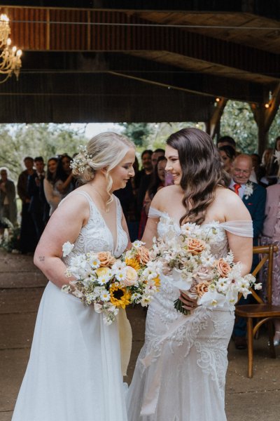 Brides holding flowers walk up steps during wedding ceremony flowers