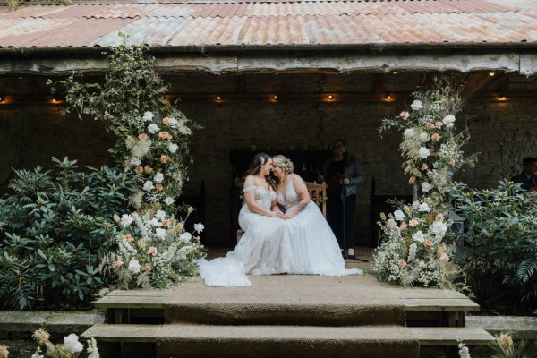 Close up of brides dress flowers surrounding them wives kiss