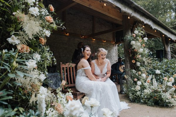 Brides wives sitting down during wedding ceremony long lace dress gown bridal flowers