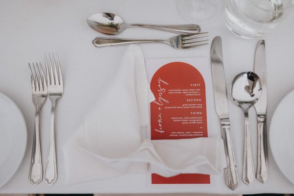 White tablecloth setting dining room flowers red menu