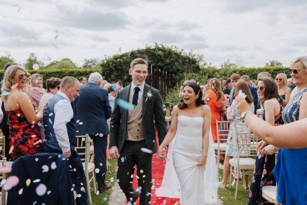 Bride and groom exit wedding just wed confetti and guests