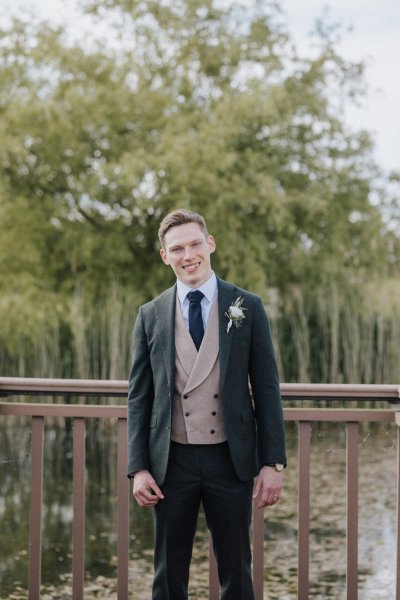 Groom wearing suit on bridge