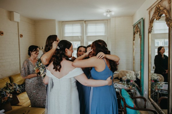 Bridesmaids hug the bride