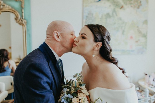 Father kisses daughter on the cheek