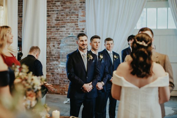 Groom and Groomsmen smile at bride