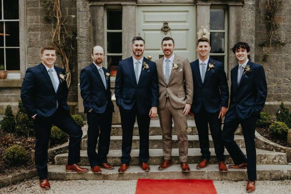 Groom and groomsmen smiling exterior shot