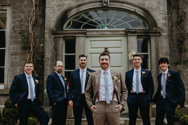 Groom and groomsmen smiling exterior shot