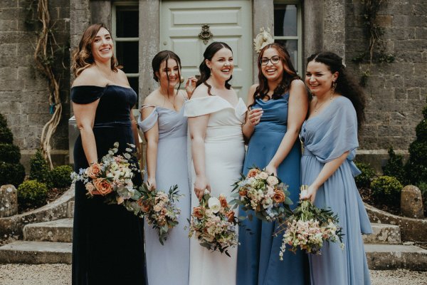 Bride bridesmaids holding flowers smiling