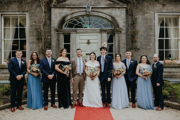 Family shot bride groom bridesmaids and groomsmen holding flowers