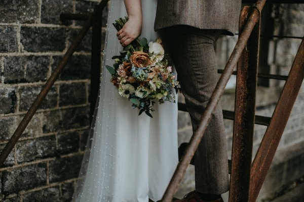 Bouquet of flowers dress and suit detail bride and groom on steps stairs