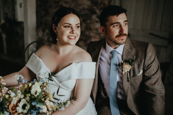 Bride and groom look to their left bouquet flowers