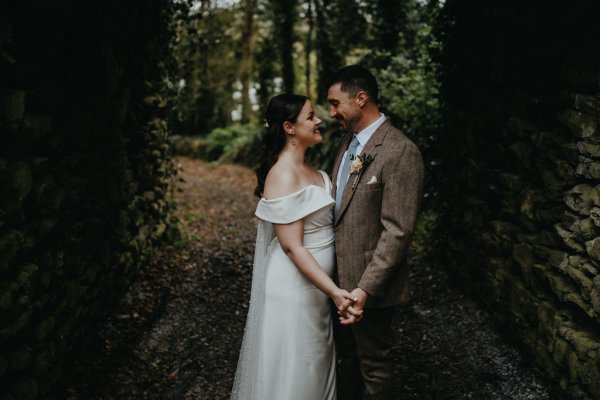 Bride and groom exterior forest park hideaway oval archway holding hands