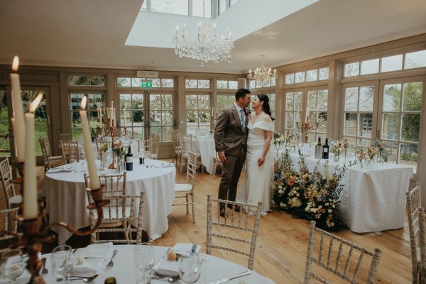 Bride and groom in the dining room chandelier hanging above