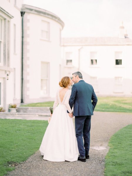 Bride and groom on grass outside venue kissing kiss