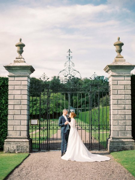 Bride and groom exterior park pillars holding hands