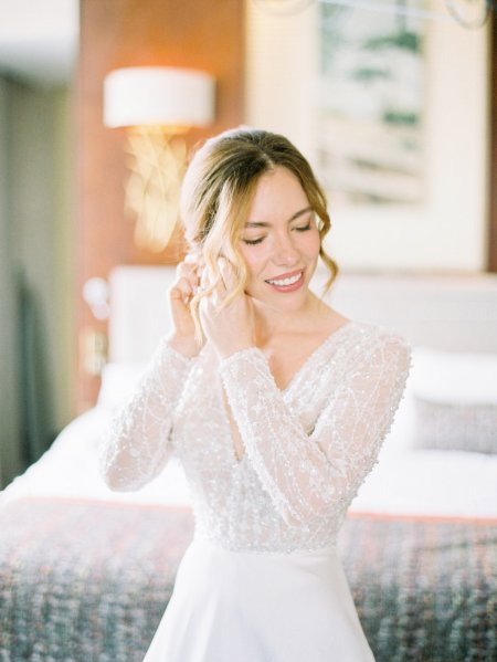 Bride interior getting ready putting on earrings