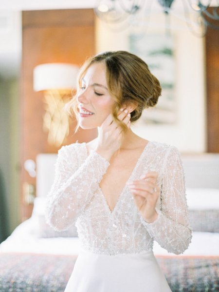 Bride interior getting ready putting on earrings