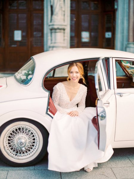 Bride outside of church beside wedding car