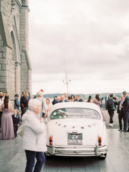 Bride and groom exiting church guests wedding car