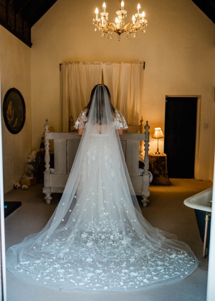 Back of bridal gown dress from behind detail dress long train in front of bed