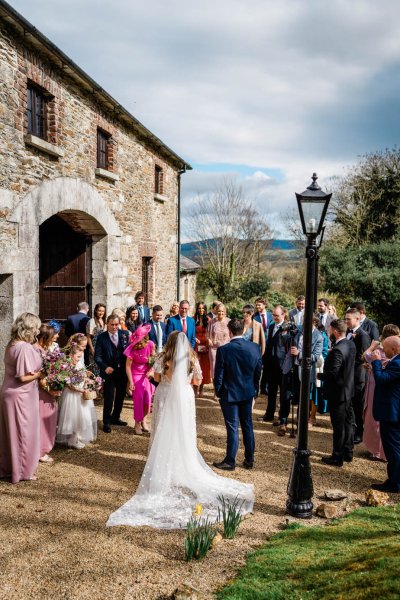 Bride and groom exterior church wedding venue with guests