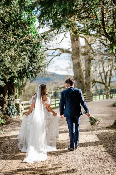 Bride and groom walking long veil from behind