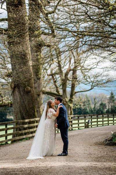 Bride and groom walking long veil from behind