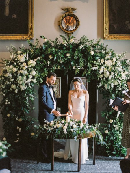 Bride and groom under bed of flowers during wedding ceremony