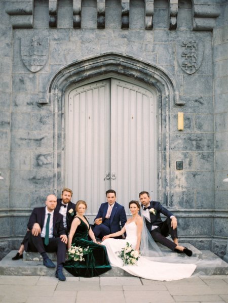 Groom bride and mother sitting on the steps father groomsmen