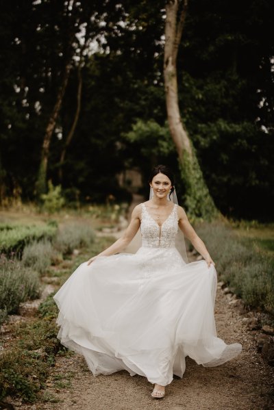 Bride running through park on pathway