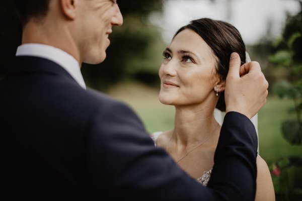 Groom puts his hand on brides hair looking at each other