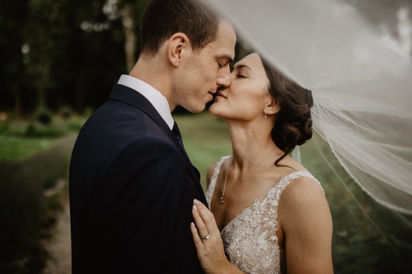 Bride and groom laugh veil blowing in wind kiss kissing