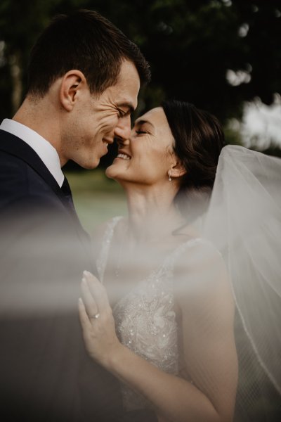 Bride and groom laugh veil blowing in wind