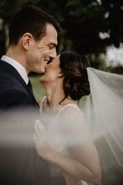 Bride and groom laugh veil blowing in wind