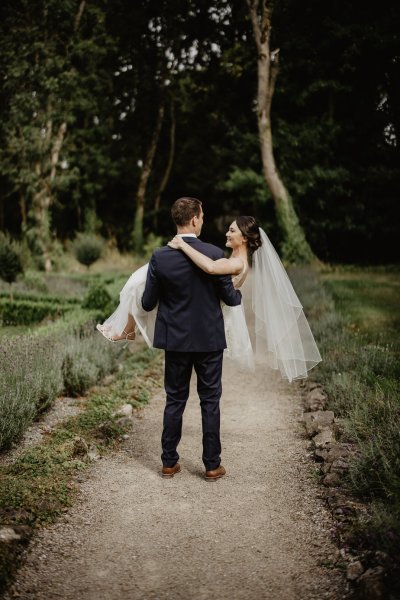 Groom carrying bride on pathway