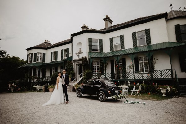 Bride and groom outside wedding venue car