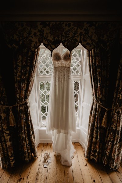 Bridal gown/dress is hanging up beside window