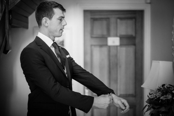 Groom getting ready suit and tie before wedding ceremony black and white