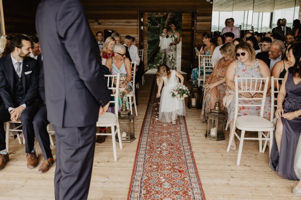 Little flower girl walks down the aisle