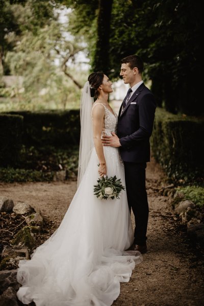 Bride and groom arms on waist holding bouquet of flowers