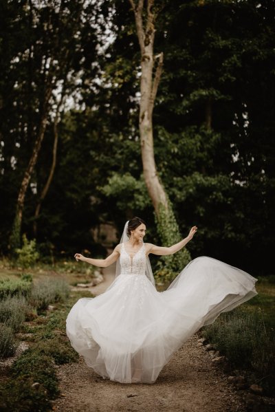 Bride running through park on pathway