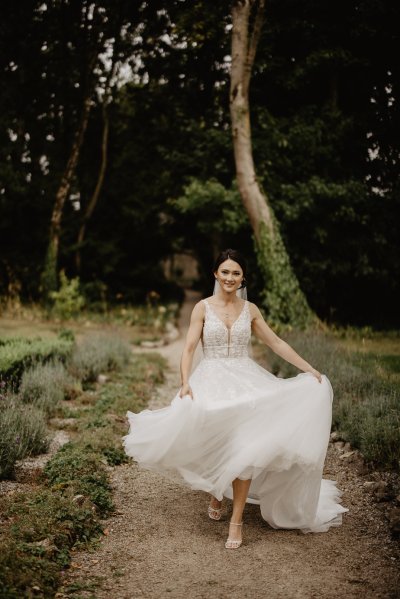 Bride running through park on pathway