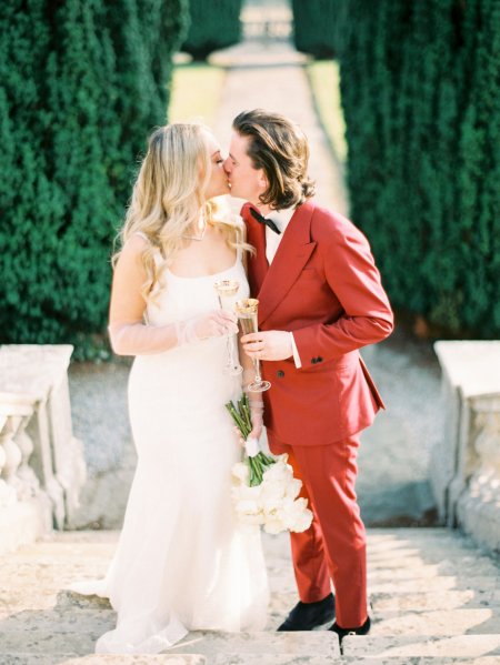 Bride and groom cheers champagne flute glasses wine kissing kiss