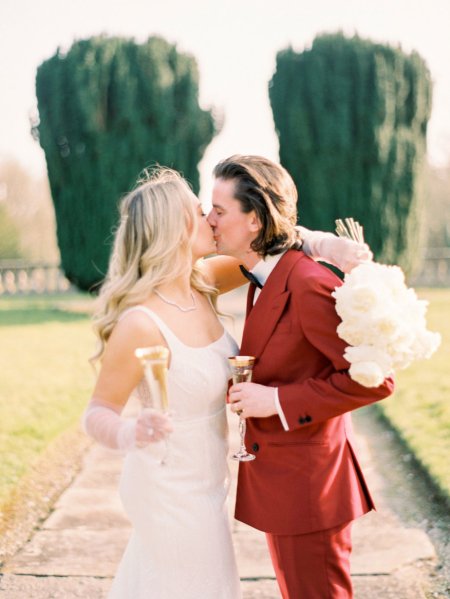 Bride and groom cheers champagne flute glasses wine kissing kiss