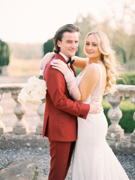 Bride and groom red suit white dress flowers exterior