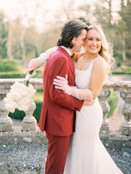 Bride and groom red suit white dress flowers exterior